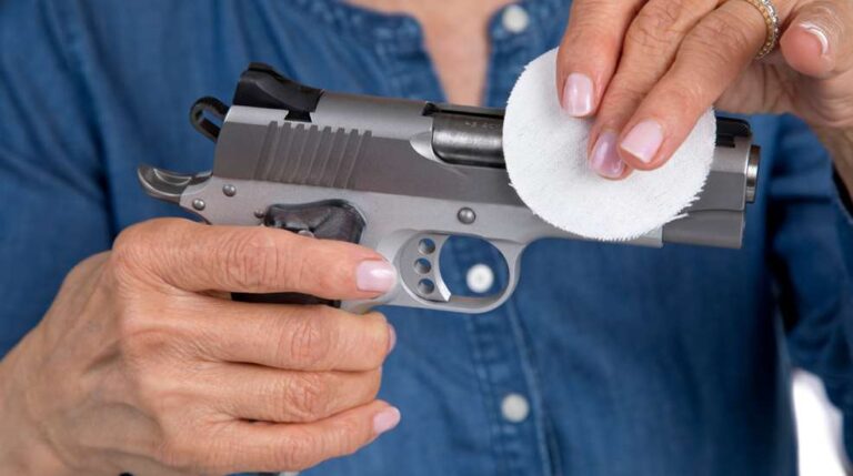 Person cleaning a handgun with a cotton pad – Gun Cleaning 101: Maintain Your Firearm in the Summer Heat
