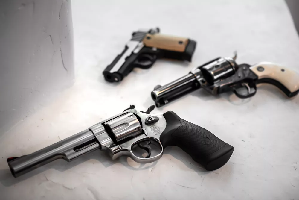 Three handguns displayed on a white surface, showcasing firearm variety and design differences.
